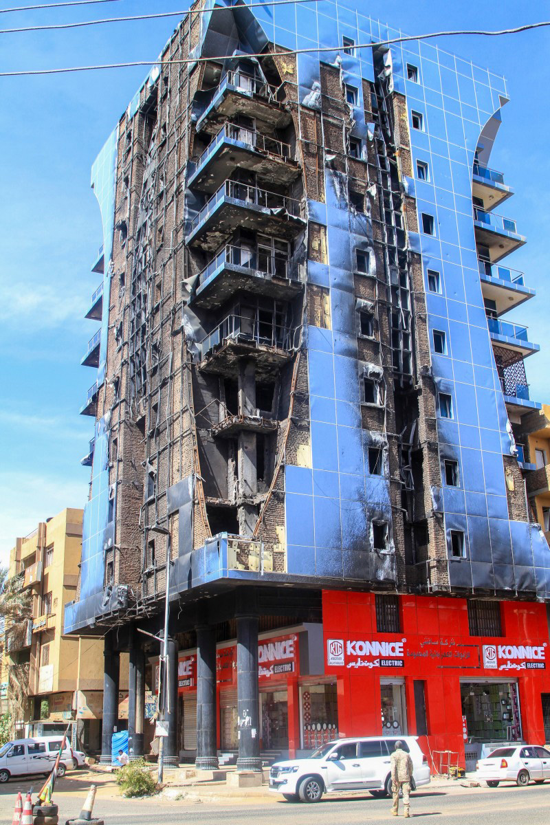 A man walks in front of a destroyed highrise building as efforts to restore the city’s infrastructure resumes after nearly three years of devastation caused by war, in the Sudanese capital Khartoum on January 17, 2026. (Photo by Ebrahim HAMID / AFP)