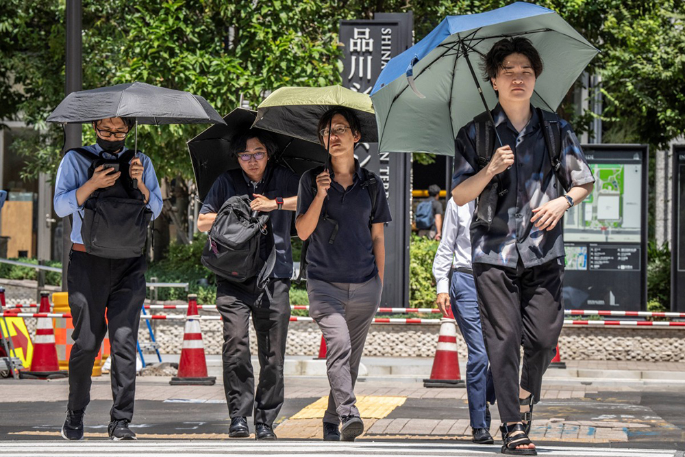 People shield themselves from the hot sun with umbrellas in Tokyo on August 27, 2025. Tokyo experienced a record 10 consecutive days of temperatures 35C or above, the weather office said on August 27. 