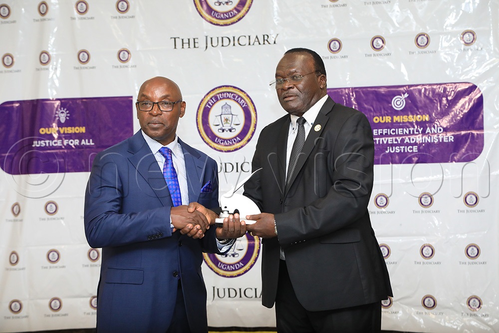 Outgoing chief Justice Alfonse Owiny-Dollo handing over instruments of power to the acting Chief Justice Flavian Zeija. (Photo by David Lukiiza)
