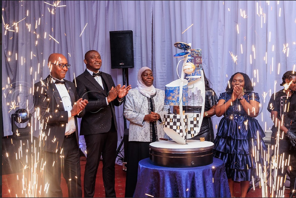 Kampala Capital City and Metropolitan Affairs Minister, Minsa Kabanda, cutting cake with the staff of CWG Uganda. (Photo by John Musenze)