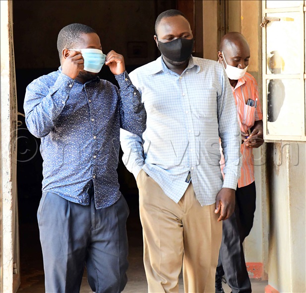Purported Mulago doctors Aloysius Wakwamunu (L) and George Patrick Ogwapiti (M) being escorted by a police detective on arrival at Wandegeya police station after they were arrested in connection with carrying an illegal surgery on a baby near Mulago Hospital on April 15,2021.