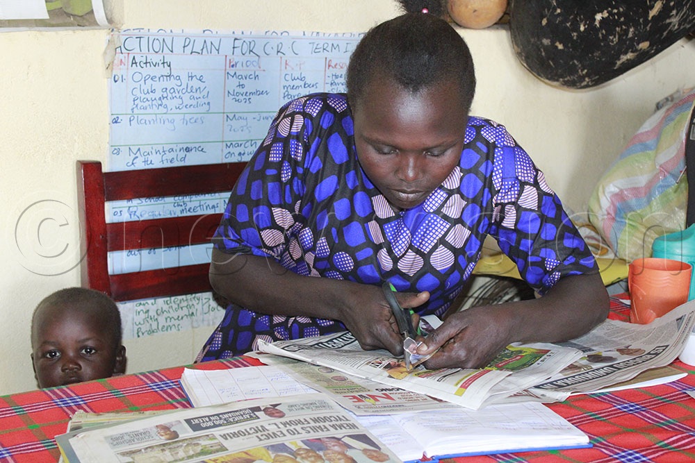 Teacher Topista Cherotin cuts out pictures to use in class at Acherer Primary school in Nakapiripirit district.