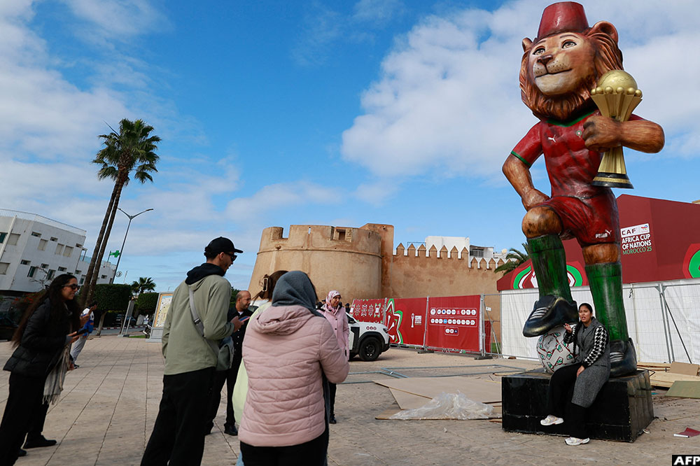 People take photographs of the official tournament mascot, 'Assad' in Rabat