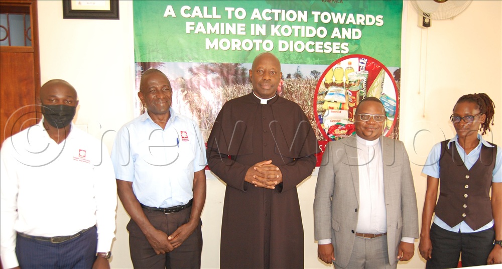 The Vicar-General of Kampala archdiocese, Msgr. Rogers Mukasa Kabuye (wearing a black cassock) shares a photo-moment with the Director of Caritas Kampala, Fr. Simon Peter Musumba (fourth-left), the Caritas Charity Office Coordinator Patrick Njala (second-left), and the Caritas volunteers, Kiweesi Simon Peter (left) and Rose Salaama (right). This was during the launching of the relief food donation campaign for Karamoja at Cardinal Nsubuga Leadership Training Center, Nsambya, in Makindye Division on Friday, July 24, 2026.