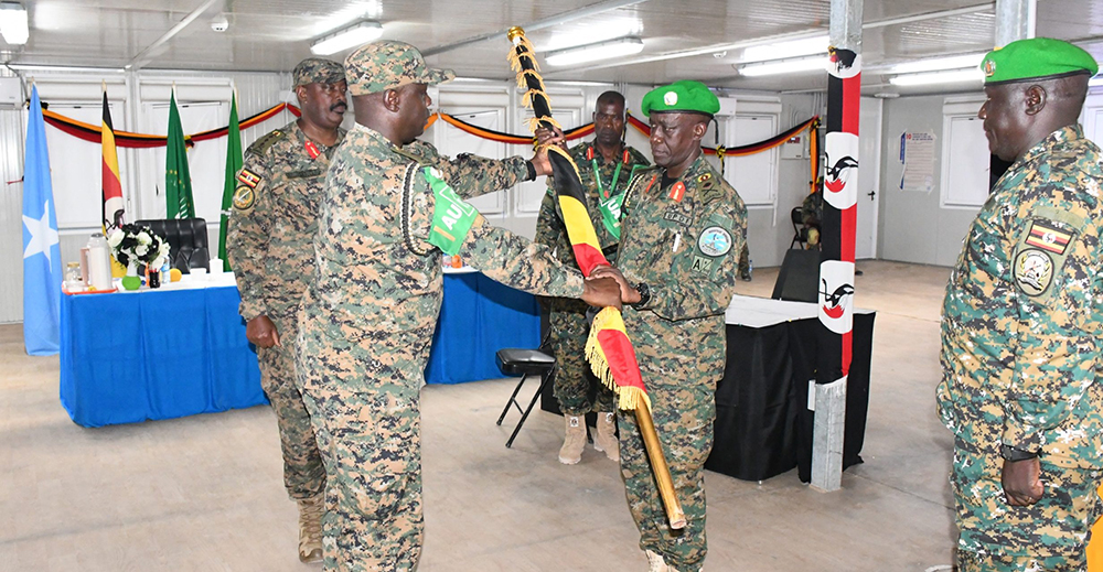 Lt Gen. Kayanja Muhanga, Commander Land Forces (CLF), witnessing the handover event as Brigadier General Joseph Ssemwanga Musoke (left) receives the national flag from Brigadier General Jackson Kayanja. (Courtesy)