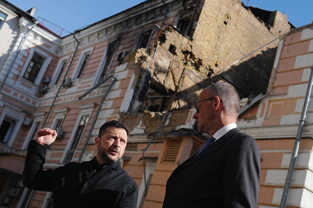 Chancellor Friedrich Merz (right, CDU), Volodymyr Zelenskyy (left), President of Ukraine, and Katherina Reiche (right, CDU) stand in front of the destroyed building of the National Academy of Sciences. (Photo by KAY NIETFELD / dpa Picture-Alliance via AFP)