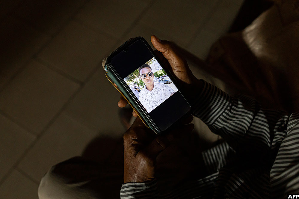 Abdoulaye Diallo shows a picture of his son Abdou Karim inside his sister's home in Guinea's capital Conakry, on September 23, 2025. (AFP)