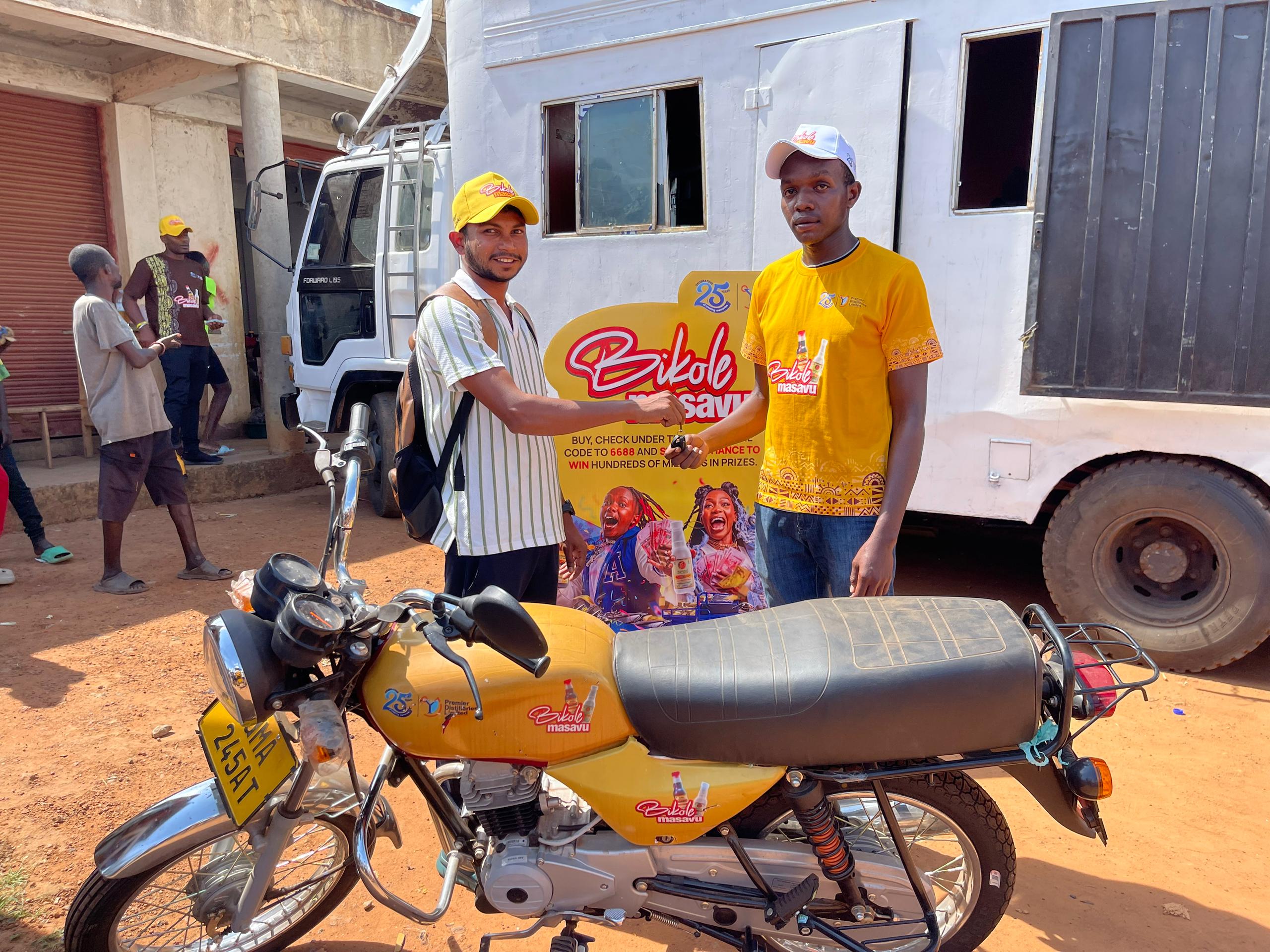 Terrance Acir (R) receives a brand new boda boda after winning from the Bikole Masavu Promotion by Premier Distilleries Limited.