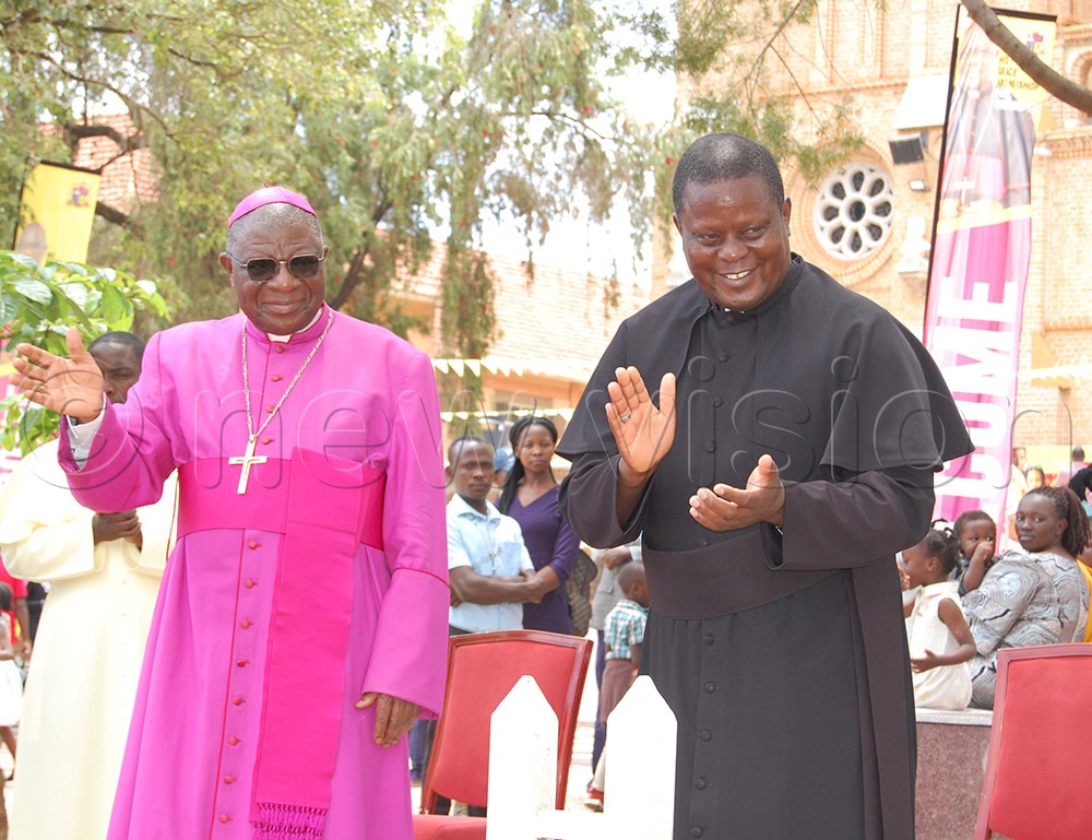 Archbishop Paul Ssemogerere (L) and Fr. Ambrose Bwangatto gesture to the children as they marched in celebration of 100 years of Lubaga Cathedral. The function took place at the Cathedral on Sunday, October 19, 2025. (Credit: Mathias Mazinga)