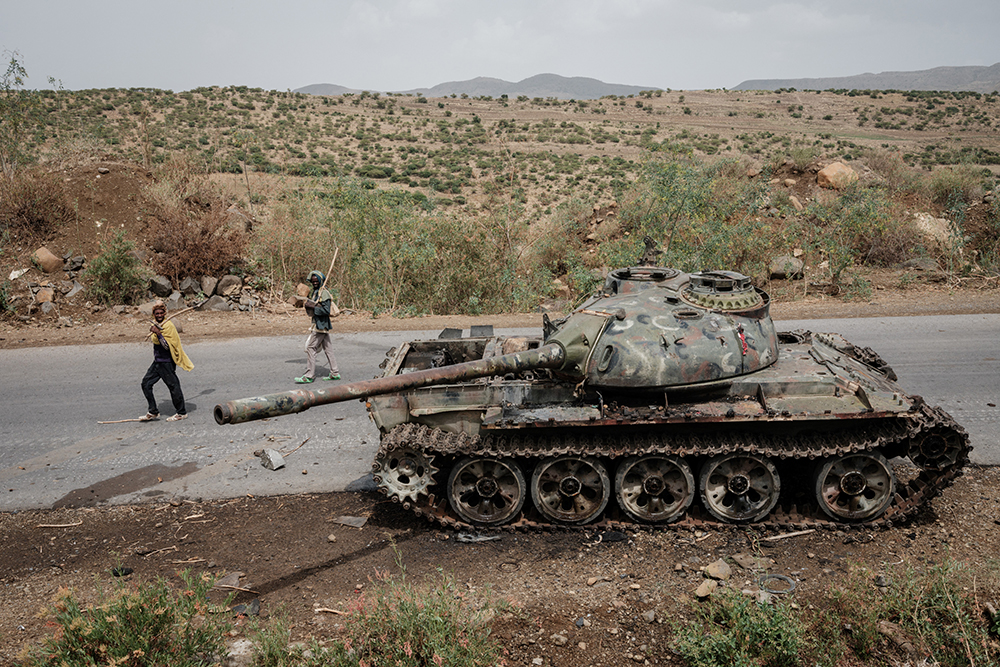 Local farmers walk next to a tank of alledged Eritrean army that is abandoned along the road in Dansa, southwest of Mekele in Tigray region, Ethiopia, on June 20, 2021.