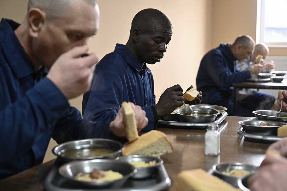   Kenyan national Evans Kibet (2nd-L), captured while fighting for Russian forces on the Ukrainian front, has his lunch at a detention center for Russian POWs in western Ukraine on November 26, 2025, amid the Russian invasion of Ukraine. (Photo by Genya SAVILOV / AFP)