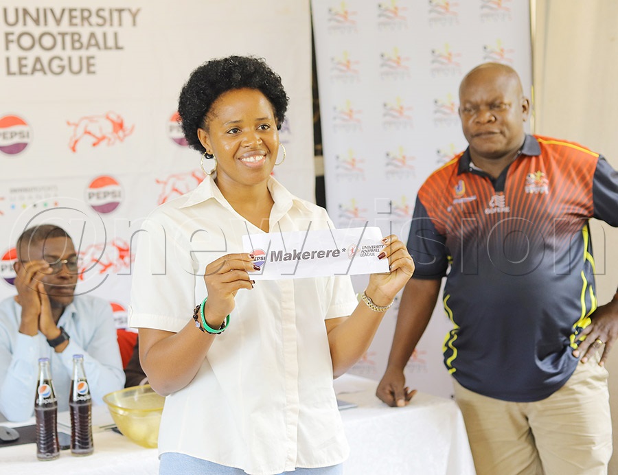 King Ceasor University Public Relations Officer Betty Uwiringiyimana makes a draw during the University Football League draws at Kati Kati Restaurant in Kampala on October 15, 2025. Looking on (right) is AUUS General Secretary Patrick Sebuliba. Photo by Johnson Were