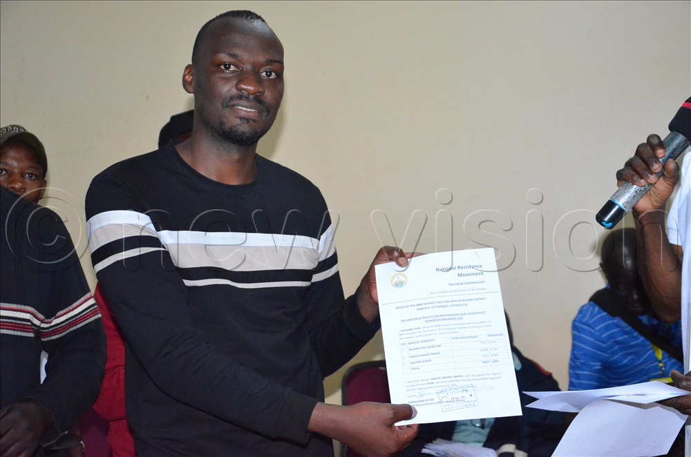 In a white T-shirt is Peter Sserwadda  the Buikwe district NRM Elections officer handing over a declaration form to Badru Kabuye Mpoza the Njeru NRM Winner.