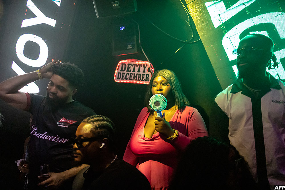  A patron uses a fan next to a sign that reads "Detty December" inside the Voyage nightclub in Ikeja, Lagos in Nigeria on December 7, 2025.