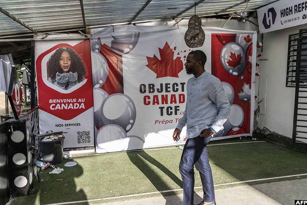 In Cameroon, a man walks past a billboard advertising the preparation to the French Comprehension Test (TCF) finalized to expatriation to Canada