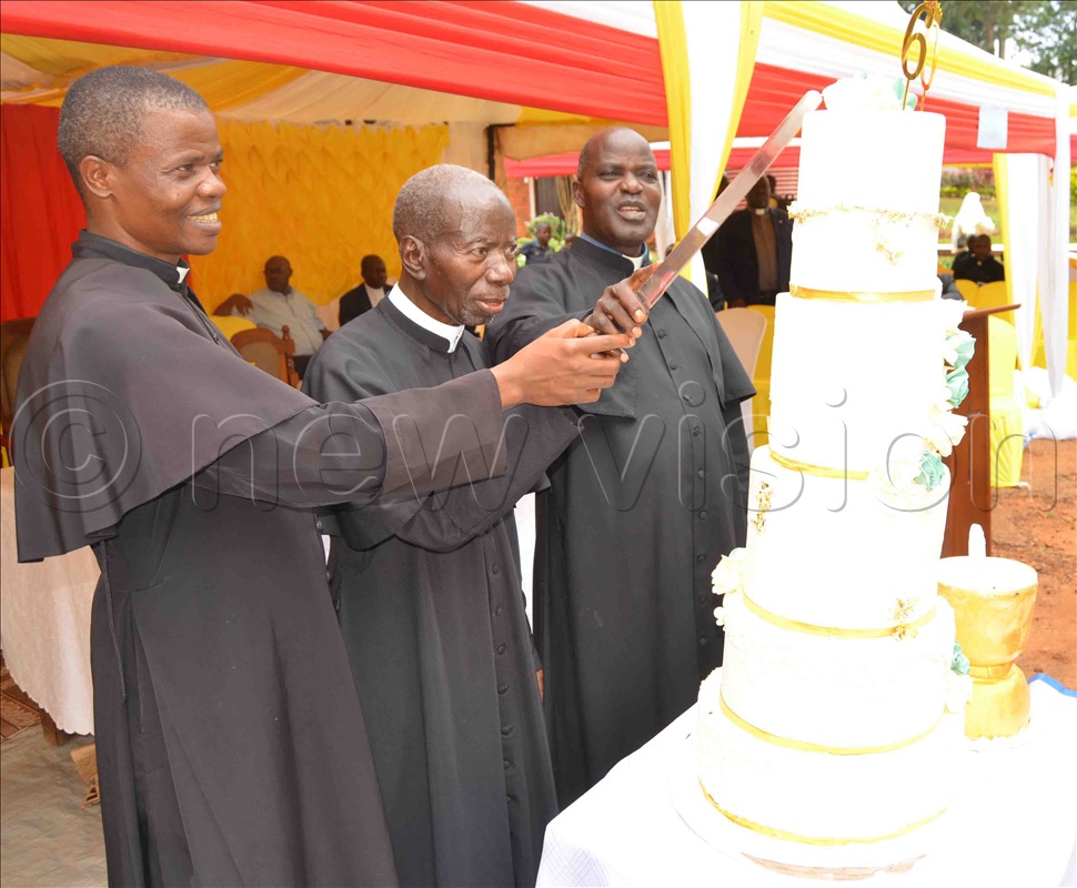 Fr. Dr. James Kabuye (centre) cuts cake with Fr. Godfrey Sseggujja (left) and Fr. Ben Mayindwe (right) during the celebration of his 60th priestly anniversary at Kiyinda-Mityana Catechetical Training Centre on December 29, 2022.