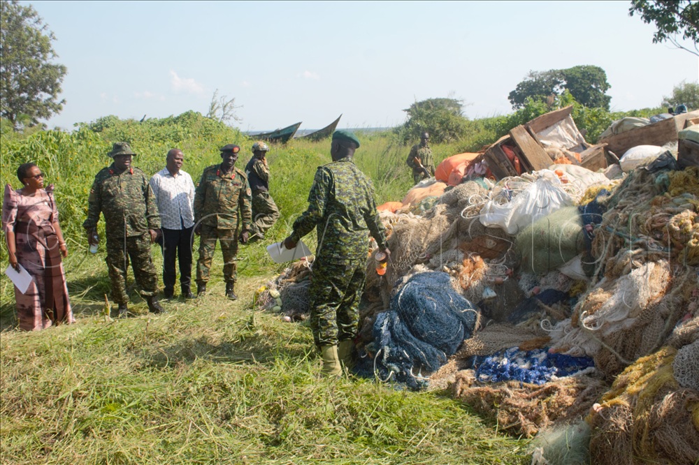 Deputy CDF Lt Gen Sam Okiding, (second left) witness the burning of the illegal fishing gears at Ssenyondo landing site.