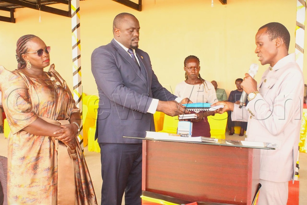 Andrew Okot, the new Chairman LC5 for Omoro, being handed documents after swearing-in. (Photo by Claude Omona)