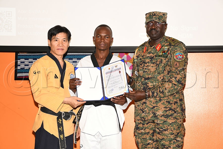 Godfrey Kutosi (centre) one of the trainees receives his certificate from head Brigadier General Wycliffe Keita (right) and trainer Kim Kwangjoo. Photo by Michael Nsubuga