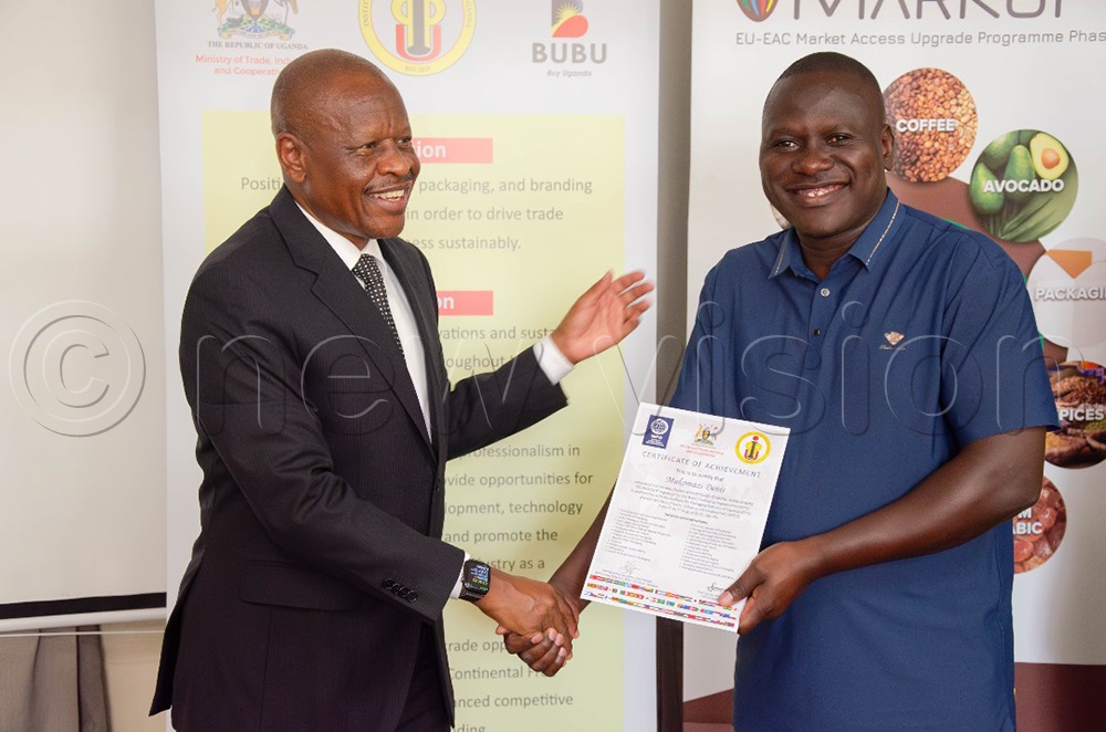 The state minister for trade and industry, Gen. Mbadi Mbasu handing over a certificate to one of the participants. (Photo by Moses Kigongo)