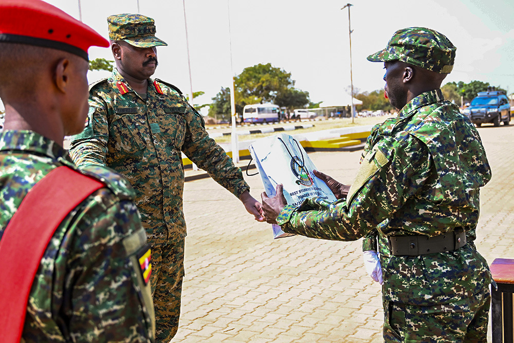 CDF Gen Muhoozi presents the Order of the Queen Award to recruit Opoka Richard, who emerged best academic student during the pass-out at Kaweweta on Thursday. (PPU Photo) pass-out ceremony