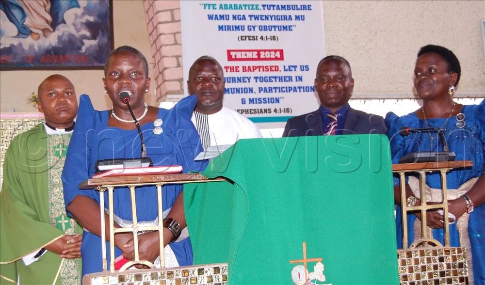 The Secretary of the SAAFU Commitee, Annet Katende (behind microphone) delivers her message. With her are members of the commitee, who include the Director  Fr. Timothy Lukananso (left), the Chairman Edward Kanyike (third-left), Michael Ssebbowa Mukasa (fourth-keft) and the head of the Laity of Kampala Archdiocese Emily Kitto Mwaka. 