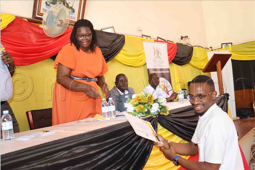 Assistant RDC of Lira Proscovia Ayo giving a certificate of attendance to one of the participants.