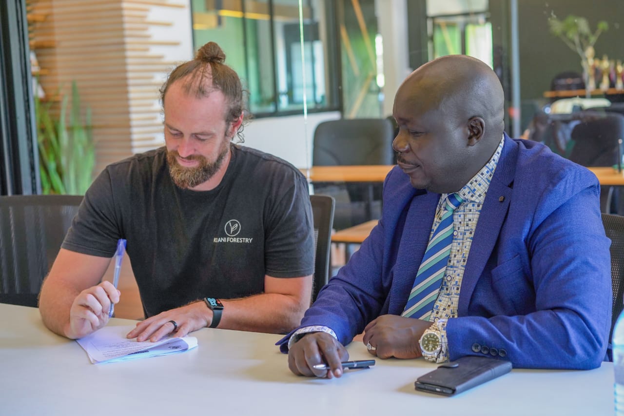 Kijani Forestry CEO Quinn Neely signing the MOU document as Muni University vice-chancellor Prof. Simon Katrini Anguma looks on.Courtesy photo