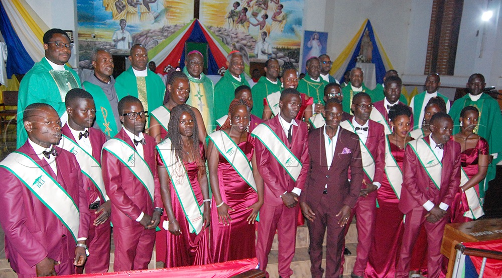 The newly-commissioned land caretakers (donning a white and green sash over maroon attire) sharing a photo-moment with the Catholic clerics after their commissioning at Our Lady of Grace Nandere Catholic parish church, in Luweero district on Friday, July 25, 2025. (Photo by Mathias Mazinga)