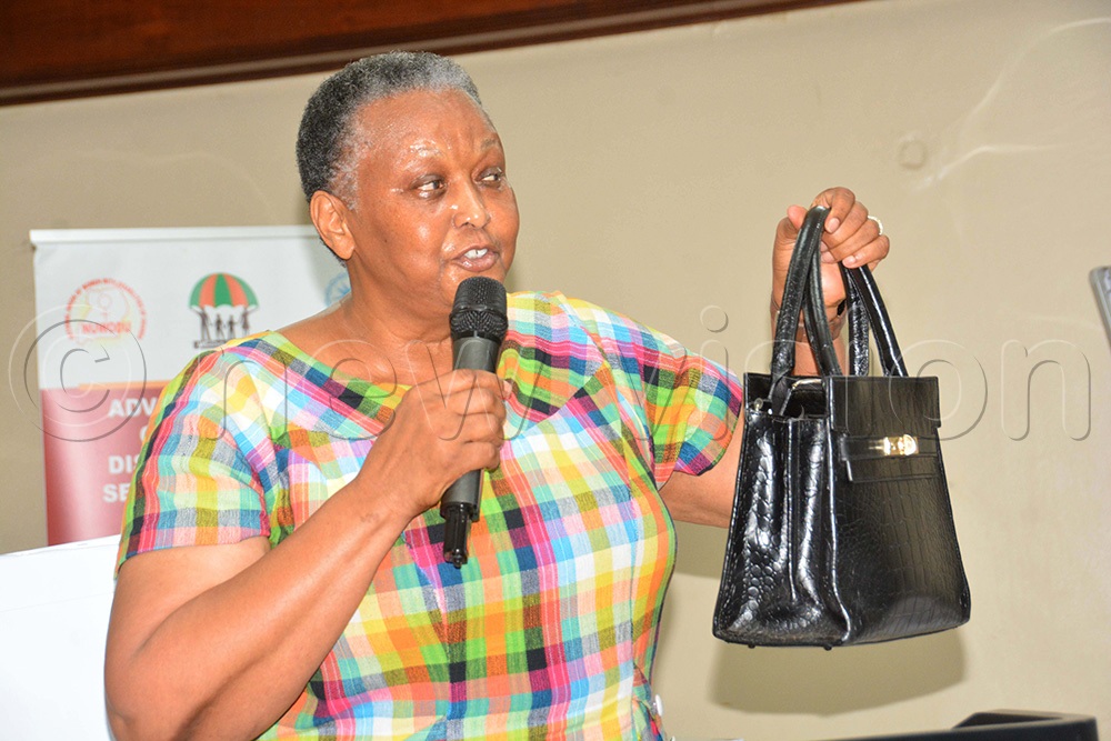 Dr Katana Mirembe, the special presidential advisor at the Presidential Initiative Skilling programme, displays a handbag made by the ghetto youth during the closure of the national stakeholders' disability inclusion meeting at Hotel Africana in Kampala. (Photo by Francis Emorut)