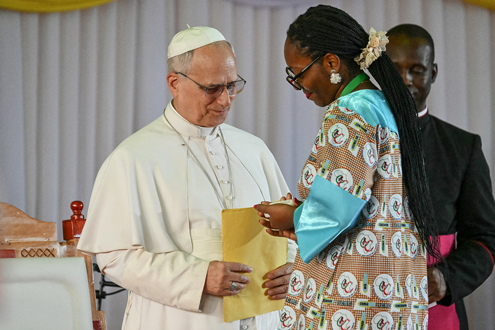 Pope Leo XIV (L) receives a gift as he meets with university students and professors at the Catholic University of Central Africa in Yaounde on the fifth day of an 11-day apostolic journey to Africa, on April 17, 2026. (Photo by Alberto PIZZOLI / AFP)