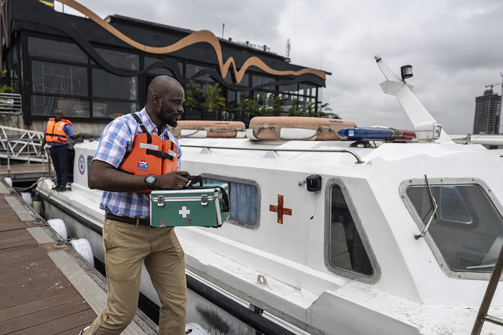 Ibrahim Famuyiwa, Lagos State waterways authority head of operations, walks holding a hard-case first aid kit next to Lagos State floating clinic that is docked at LASWA boat jetty in Lagos, on August 26, 2025. (Photo by OLYMPIA DE MAISMONT / AFP)