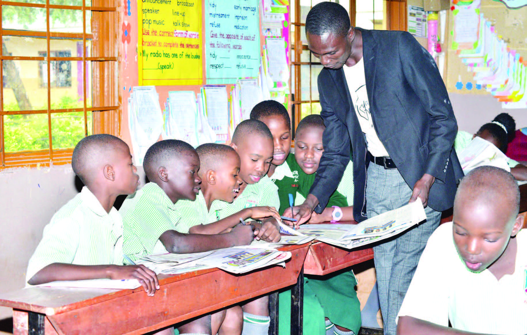 Alex Katende, Omusomesa W’essomero Lya Strathearn Primary School E Masanafu Ng’ayambako Abayizi Okusoma Nga Bakozesa Akatabo Ka Pass Ple.