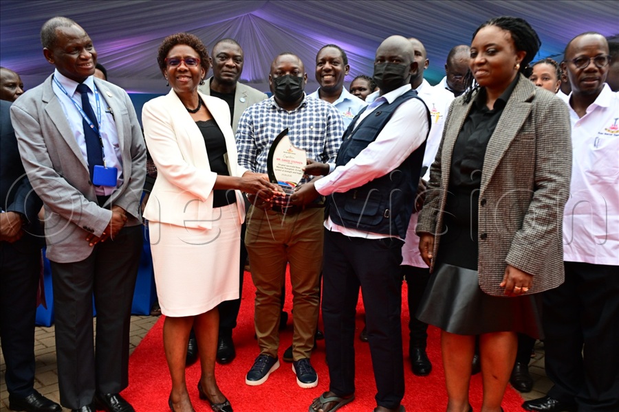 Health minister Ruth Aceng hands over a congratulatory pleque of courage, strength and hope to the first bone marrow transplant patient, Stephen Sande, upon his discharge from Uganda Cancer Institute.