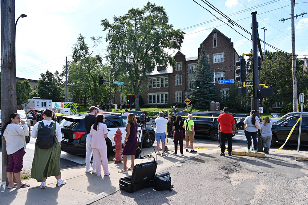 Bystanders and media look on near the scene of a shooting at Annunciation Catholic School in Minneapolis, Minneosta, on August 27, 2025. (Photo by TOM BAKER / AFP)