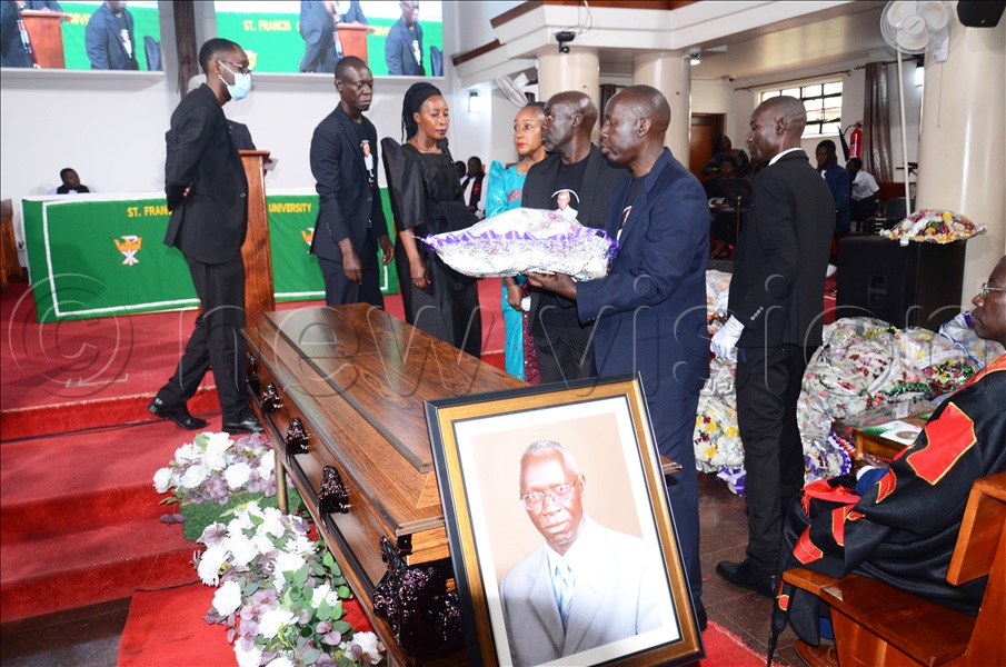 The deceased's children laying a wreath at their father's casket during prayers at Makerere. (Credit: Isaac Nuwagaba)