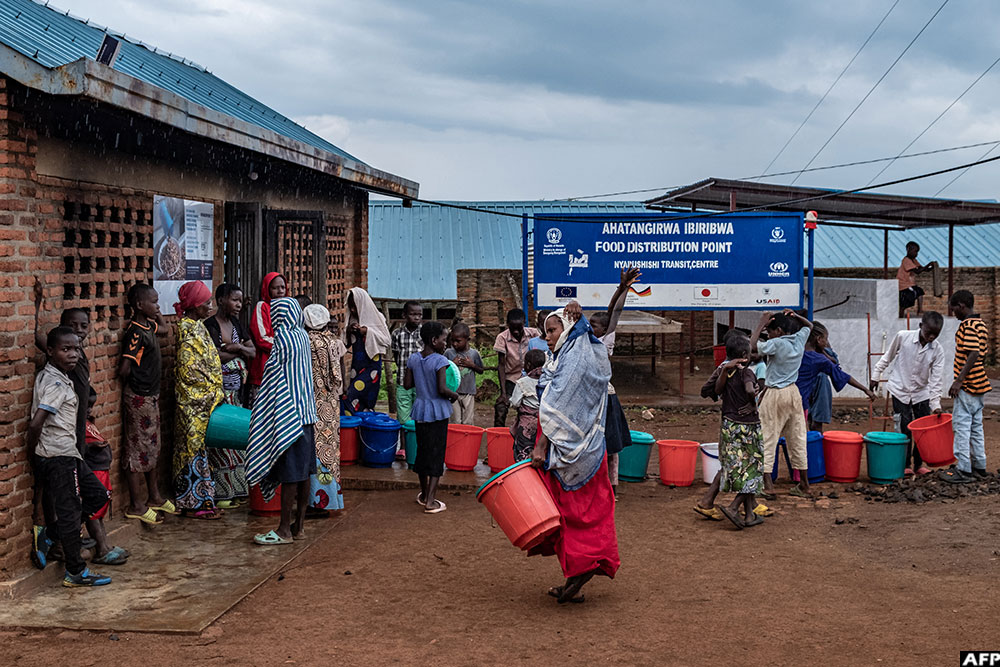 Refugees from eastern DR Congo line up with buckets at a food distribution point at Nyarushishi Transit Camp in Rusizi district, Rwanda on December 11, 2025.