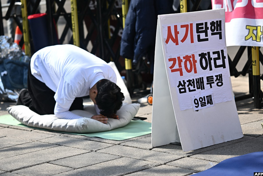 A supporter of impeached South Korean President Yoon Suk Yeol prays near the entrance of the Constitutional Court in Seoul on April 1, 2025. (AFP)