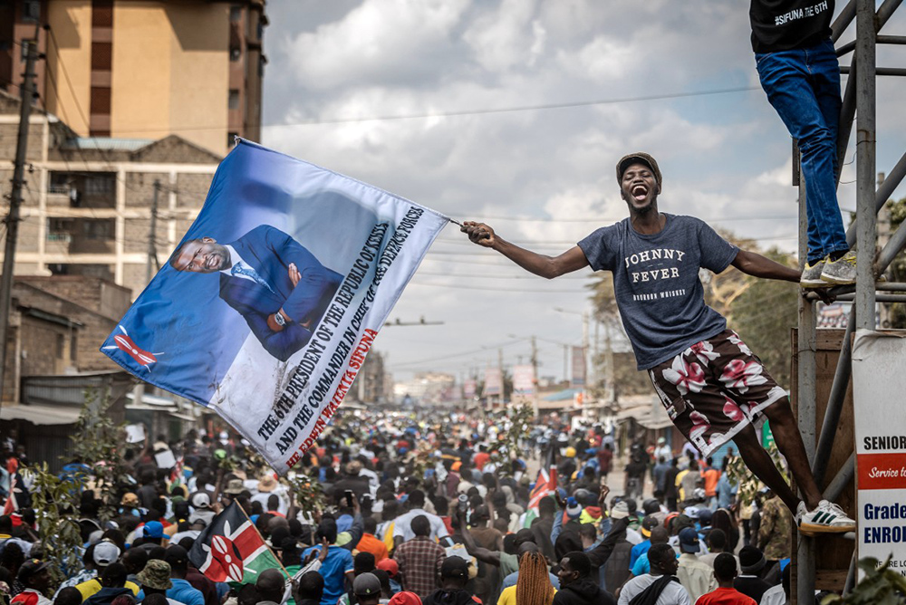 A supporter of Kenyan opposition figure and Nairobi Senator Edwin Sifuna from the Linda Mwananchi (Protect Citizens) coalition holds a flag depicting Sifuna as the next Kenyan president as large crowds follow an opposition road rally in Nairobi on September 13, 2026. (Credit: AFP)