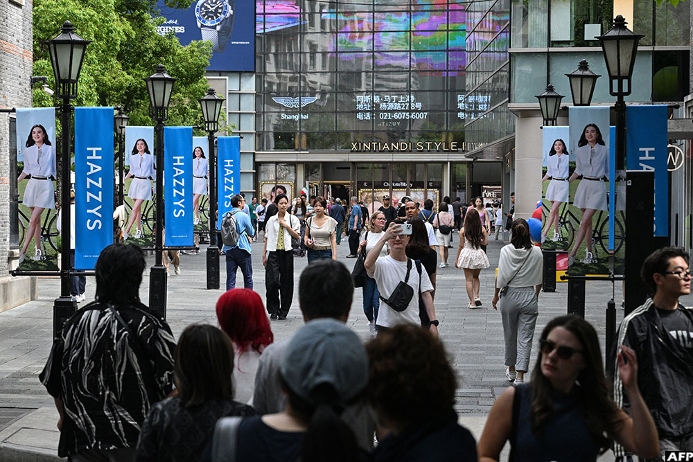 People walk on a street with luxury brand shops and a shopping mall in Shanghai.