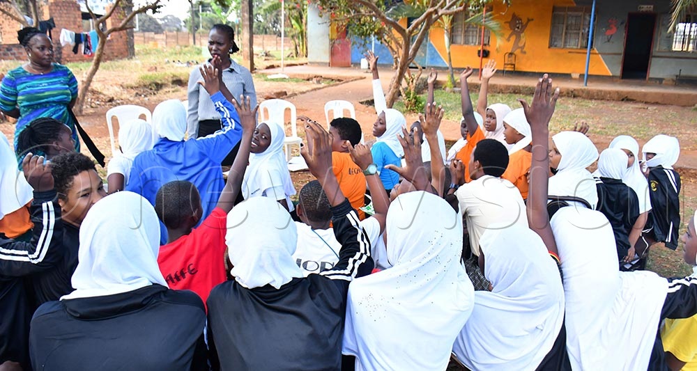 By show of hands, pupils of Multiple Junior School raise up their hands to show that they were beaten by their teachers, before State Minister for Youth and Children Affairs Mercy Faith Lakisa (C) and SP Monica Mbakire (L) the Officer in Charge of the Children and Family Protection Unit as they were interacting with the primary 5 pupils during her surprise visit at Multiple Junior school on July 14th in Jinja City. (Credit: Donald Kiirya)