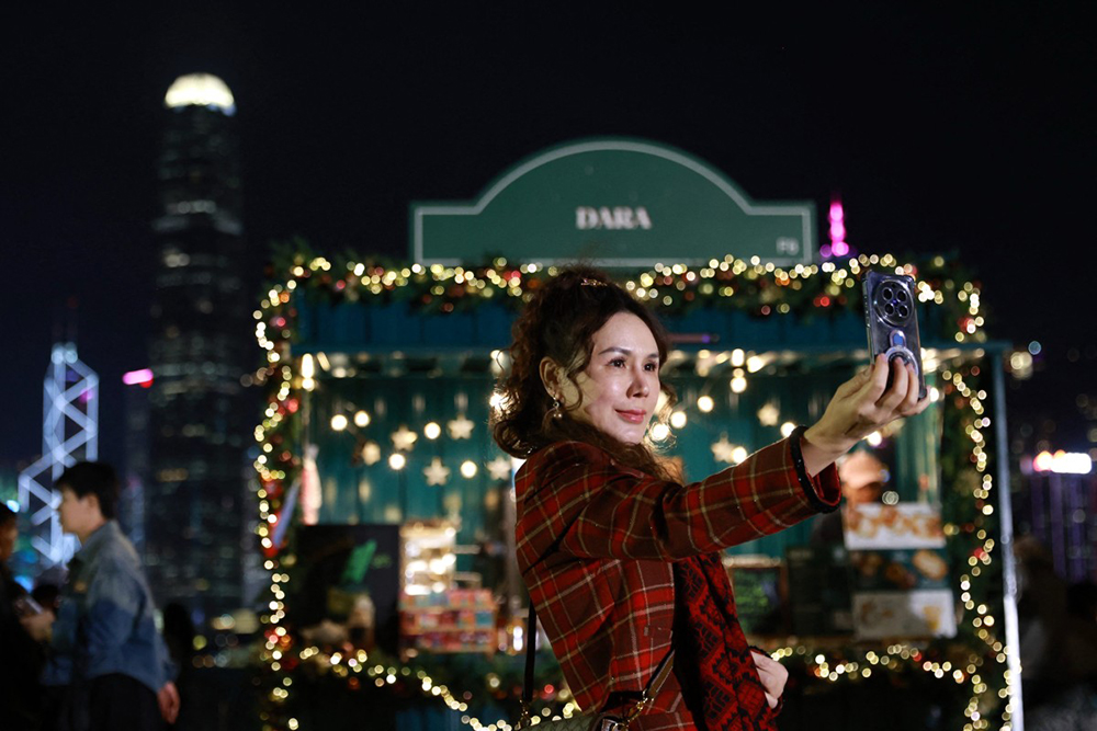 A reveller takes selfies as she waits for the midnight countdown during New Year&rsquo;s celebrations in Hong Kong on December 31, 2025. (AFP)