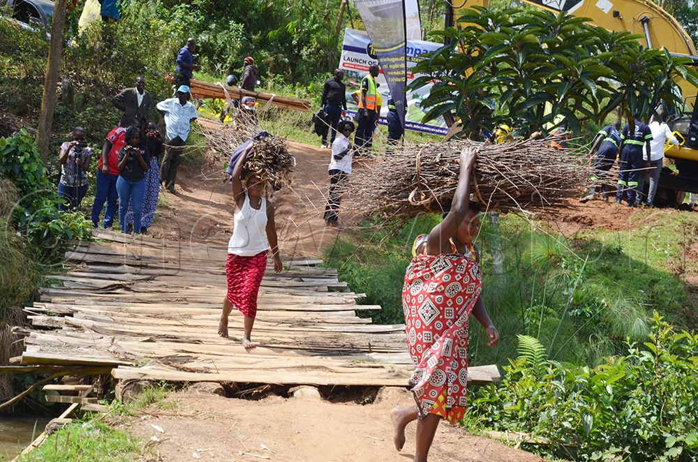 Two women cross the temporary Ncwera bridge that was constructed by the locals after their bridge was washed away by floods in 2021. (Photo by Abdulkarim Ssengendo)