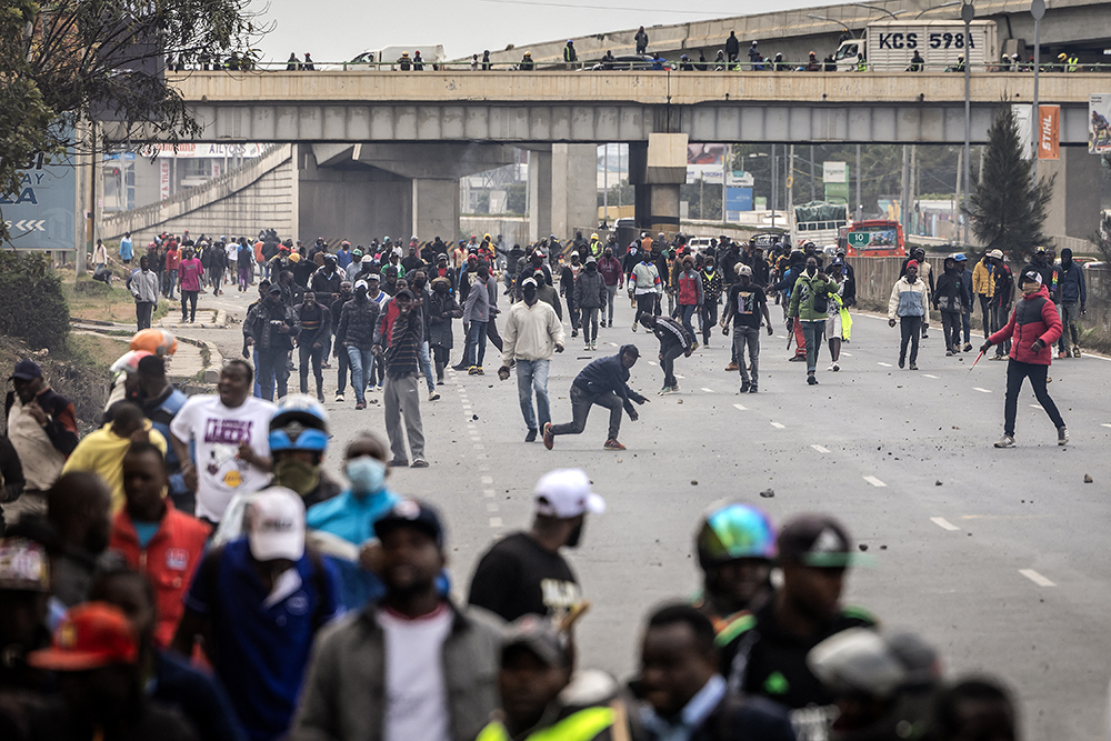  Men throw stones during clashes with supporters of former Deputy President and opposition leader of the Democracy for the Citizens Party (DCP), Rigathi Gachagua, as they block a main road while following his convoy upon his arrival in Nairobi on August 21, 2025. 