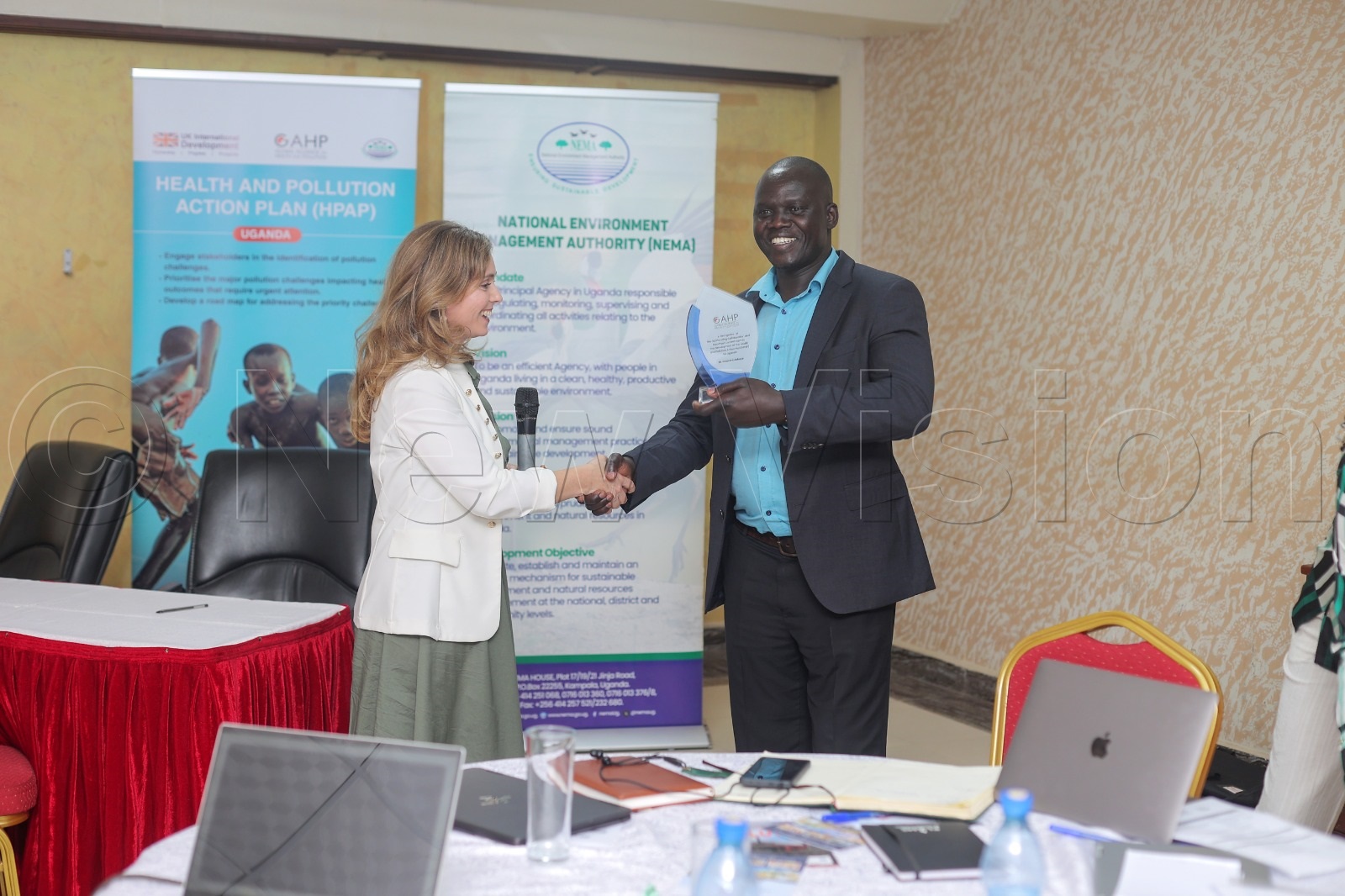 The executive director, GAPH Maria Paola, handing over an accolade to Innocent Achaye from NEMA during the inception meeting. (Credit: Agnes Kyotalengerire)
