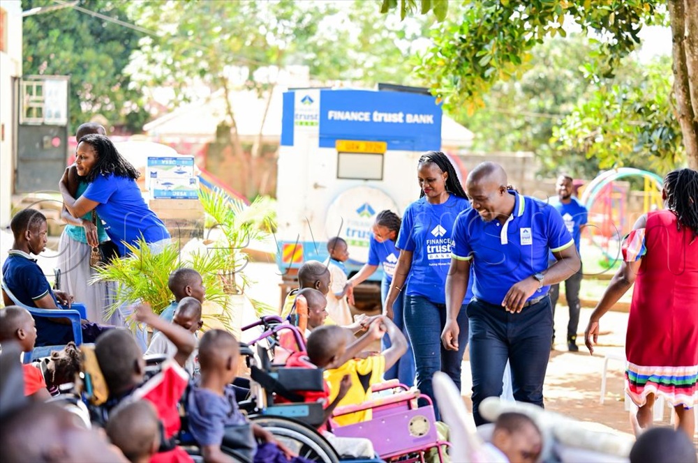  The ED Finance Trust Bank Executive Director, Annette Kiggundu and another FTB staff interact with physically challenged children. 