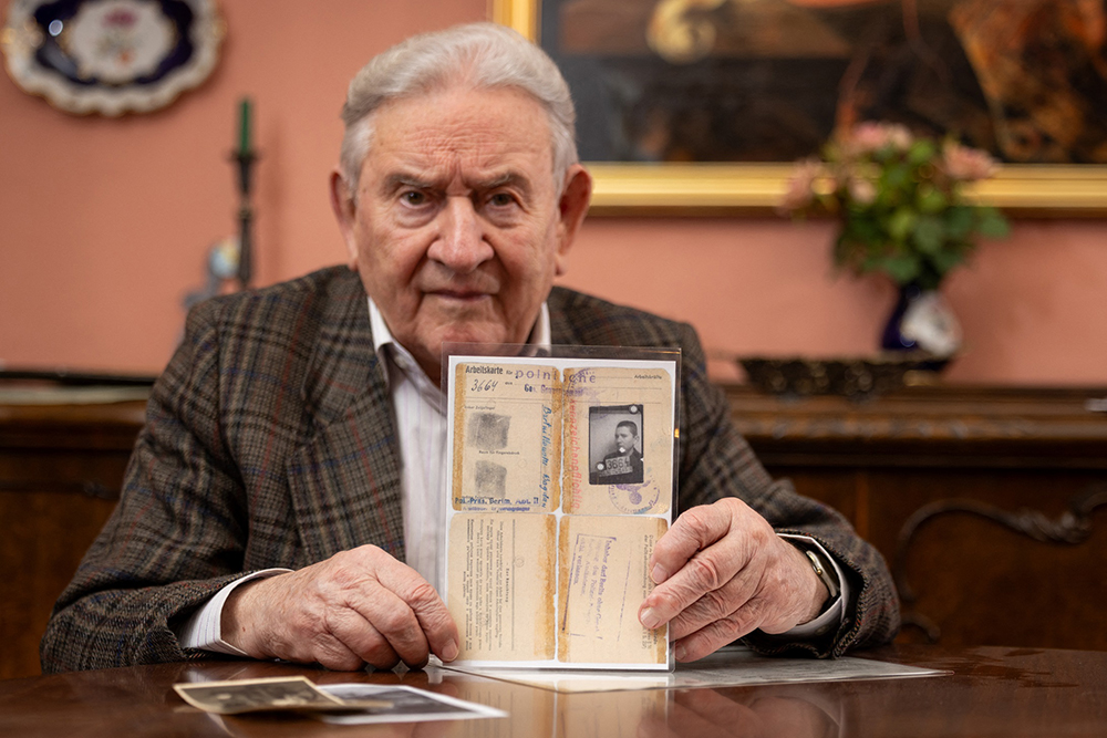 Pole Bogdan Bartnikowski, 92, a concentration camp survivor who was born in Warsaw on January 24, 1932, holds his "Arbeitskarte" - labour card identity document issued by the Germans to forced foreign workers as he poses at his home in Zalesie Gorne, south of Warsaw, Poland on January 8, 2025. (AFP)