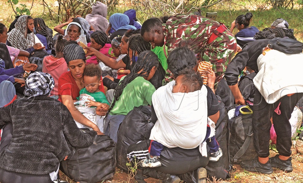  A Kenyan female soldier inspecting the luggage of Eritrean immigrant women who were abandoned in the wilderness at the Uganda-Kenya border. (Credit: File/Olandason Wanyama)