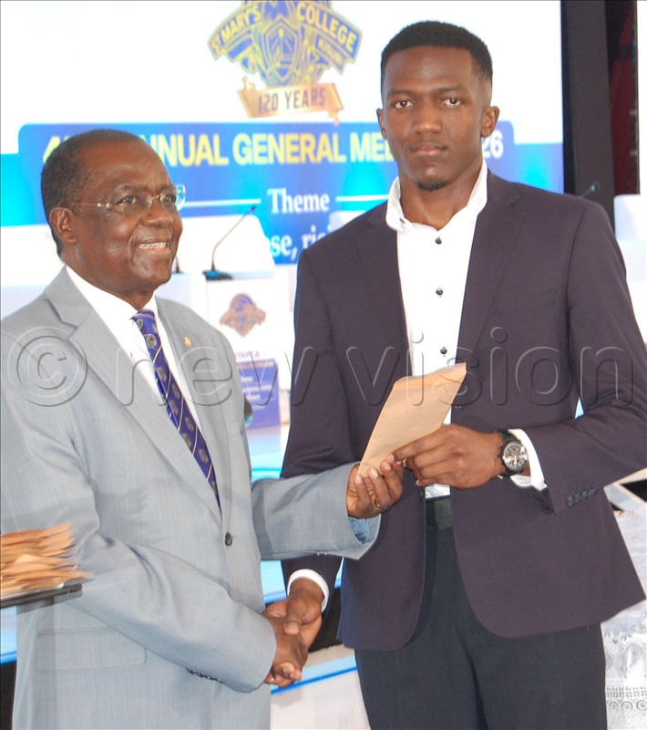 The Chairman of SMACK's Board of Governors, Dr. Saturninus Kasozi Mulindwa giffts one of the students who performed exceptionally well in last year's UNEB examinations.