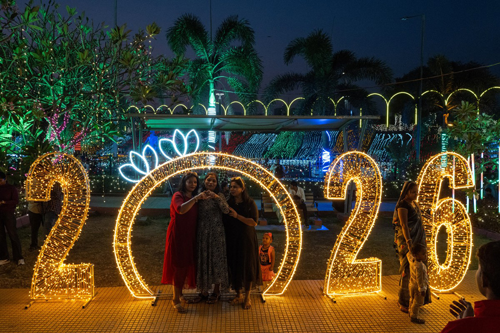 Revellers pose for photographs at an illuminated sea promenade during New Year's Eve in Mumbai on December 31, 2025. (AFP)